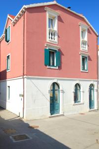 un bâtiment rouge et blanc avec des portes et des fenêtres vertes dans l'établissement Vila Mila, à Vela Luka