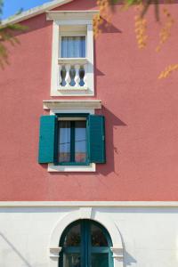 un bâtiment rouge avec une fenêtre avec un volet vert dans l'établissement Vila Mila, à Vela Luka