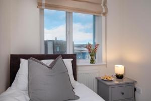 a bed with a pillow and a window with a vase of flowers at Pilot Wharf in Exmouth