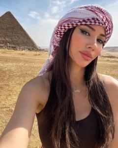 a young woman wearing a head scarf standing in front of the pyramids at New fort Night Pyramids Hotel in Giza