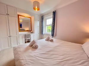 a bedroom with a large white bed with towels on it at Thimble Cottage in Sidmouth