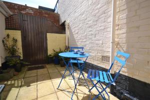 two blue chairs and a table on a patio at Thimble Cottage in Sidmouth
