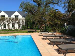 a swimming pool with lounge chairs and a house at La Jolie Dauphine Guest House in Franschhoek