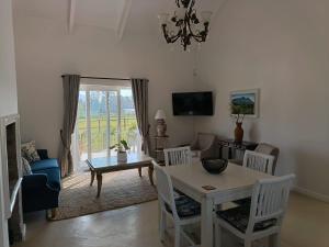 a living room with a table and chairs and a tv at La Jolie Dauphine Guest House in Franschhoek