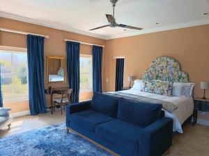 a bedroom with a bed and a blue couch at La Jolie Dauphine Guest House in Franschhoek +69 photos
