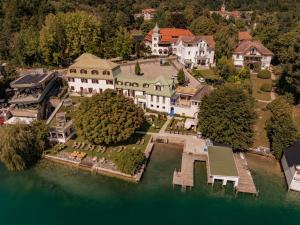 una vista aérea de una mansión en un lago en Strandhotel Kärntnerhof, en Pörtschach am Wörthersee