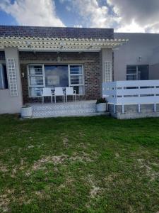 a house with two white benches in the yard at StruisPlace in Struisbaai
