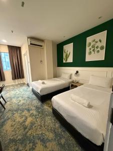 um quarto de hotel com duas camas e paredes verdes em Asto Hotels Kuala Lumpur em Kuala Lumpur