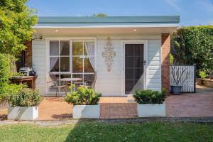 a house with a patio with a table and chairs at Fairy Nook - Charming Granny Flat with Shared Garden in Mayfield