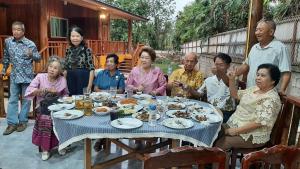 a group of people sitting around a table eating food at Baan Berm Family Inn  +8 photos