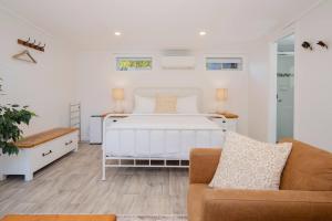 a white bedroom with a bed and a couch at Fairy Nook - Charming Granny Flat with Shared Garden in Mayfield