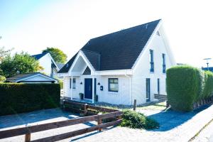 a white house with a black roof and a fence at Komforthaus Wendt Timmendorfer Strand in Timmendorfer Strand