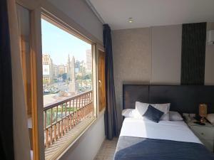 カイロにあるLotus Al-Tahrir hotelのベッドと大きな窓があるホテルの部屋
