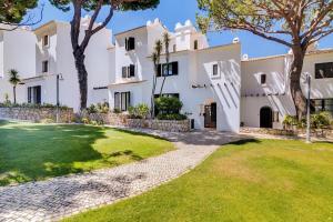 a large white house with a green yard at Pine Cliffs Village in Albufeira