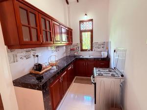 a kitchen with wooden cabinets and a black counter top at Transit villa 10 minutes drive from the Airport in Katunayake +13 photos