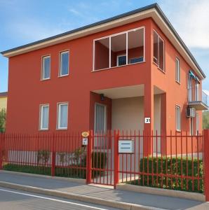 ロッツァーノにあるLa Maison di Grace vicino Humanitas & Forumの赤柵付赤い家