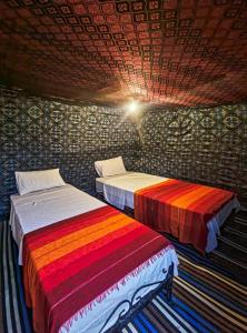 2 camas en una habitación con sábanas multicolores en Merzouga Standard Bivouac, en Merzouga