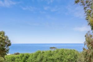 a view of the ocean from behind some trees at Spacious Seaview Family Getaway in Torquay