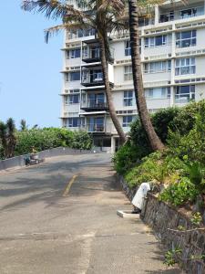 a parking lot in front of a building with palm trees at The Beach Nook - Umdloti Holiday Resort in Umdloti