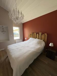 a bedroom with a large white bed and a chandelier at Le Chai des Poilanes in Liré