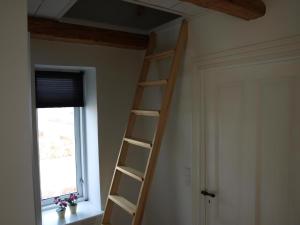 a wooden ladder in a room with a window at Super Apartment In The First Row With A 180-Degree Sea View in Spodsbjerg