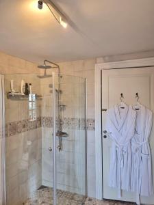 a bathroom with a shower and a robe on a door at "Kornloftet", A Beautiful Home Built In The Old Barn At Frishøjgaard in Østerby