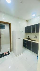a white kitchen with a refrigerator and a sink at الماسة الروز للشقق المخدومة in Najran