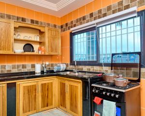 a kitchen with wooden cabinets and a stove at Résidence meublée kribi in Kribi