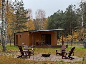 a cabin with three chairs and a fire pit in front of it at MISI domek in Kadłubówka