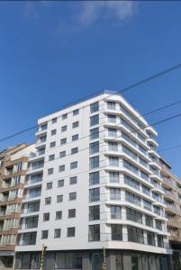 a tall white building with a blue sky at Luxueus nieuw zonnig hoekappartement SEAVIEW Heldenplein - ruime garagebox - 2 fietsen in Knokke-Heist