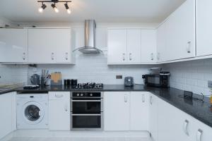 a kitchen with white cabinets and a stove top oven at Open Mind Property - 3 Bed Home with Free Parking in Portsmouth +12 photos