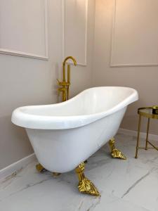 eine weiße Badewanne mit goldenen Beinen im Bad in der Unterkunft Golden Eden Wieniawska - Rezydencja Ogród Saski in Lublin