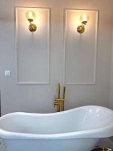 eine weiße Badewanne im Bad mit zwei Leuchten in der Unterkunft Golden Eden Wieniawska - Rezydencja Ogród Saski in Lublin + 31 Fotos