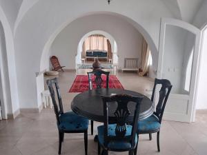 Un comedor con mesa y sillas y un dormitorio. en Dar El kharrouba, en Hammamet Nord