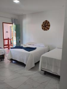 a bedroom with two beds and a clock on the wall at Pousada Renascer in Marau +17 photos