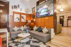 a woman sitting on a couch in a living room at FabHotel JDM Residency in Gurgaon