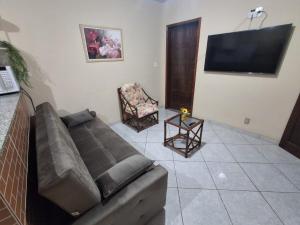 a living room with a couch and a flat screen tv at Casa com Piscina no Centro de Unamar em Cabo Frio in Cabo Frio
