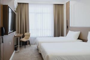 une chambre d'hôtel avec deux lits et une télévision dans l'établissement Bon Hotel Bishkek, à Bishkek
