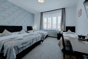 a bedroom with two beds and a desk and a window at 7Days B&B in Bratislava +3 photos