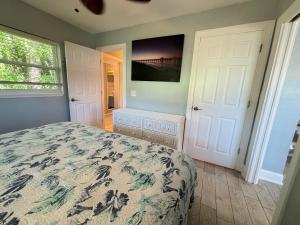 ボニータ・スプリングスにあるSand Dollar Updated Kitchen Washer Dryer On River 1 Mile to Beach Sleeps 4のベッドと壁にテレビが掛かった寝室