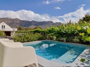 a swimming pool with chairs and mountains in the background at The Barn On 62 - Cottages in Montagu