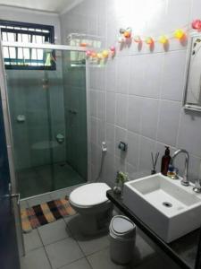 a bathroom with a shower and a toilet and a sink at Casa Vilarejo, cond fech, ar cond, churrasq, piscina in São Sebastião