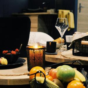 une table avec une bougie, des fruits et un verre dans l'établissement Appartement avec spa privatif, à Douai