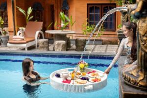 a woman and a little girl in a swimming pool at Lumbung Sari Hotel Legian in Legian