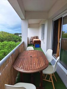 Una mesa y sillas de madera en un balcón. en Les grands prés, en Aytré
