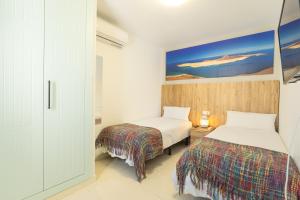 een slaapkamer met twee bedden en een schilderij aan de muur bij Villa Piva in Playa Blanca +13 foto's