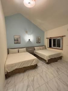 2 camas en un dormitorio con una pared azul en 墾丁高都莊園, en Nanwan