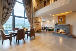 a living room with a table and a fireplace at SaffronStays Pebble House - 3BR riverside villa with glass walls, terraces & Nun River views, Dehradun in Dehradun
