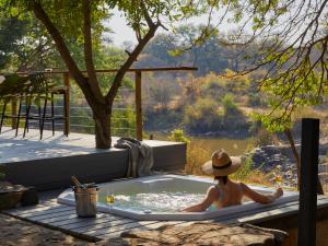 a woman in a jacuzzi tub on a deck at Toro River by NEWMARK in Makalali Game Reserve