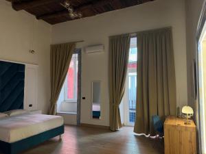 a bedroom with a bed and two large windows at Chiaia Lifestyle Suite in Naples